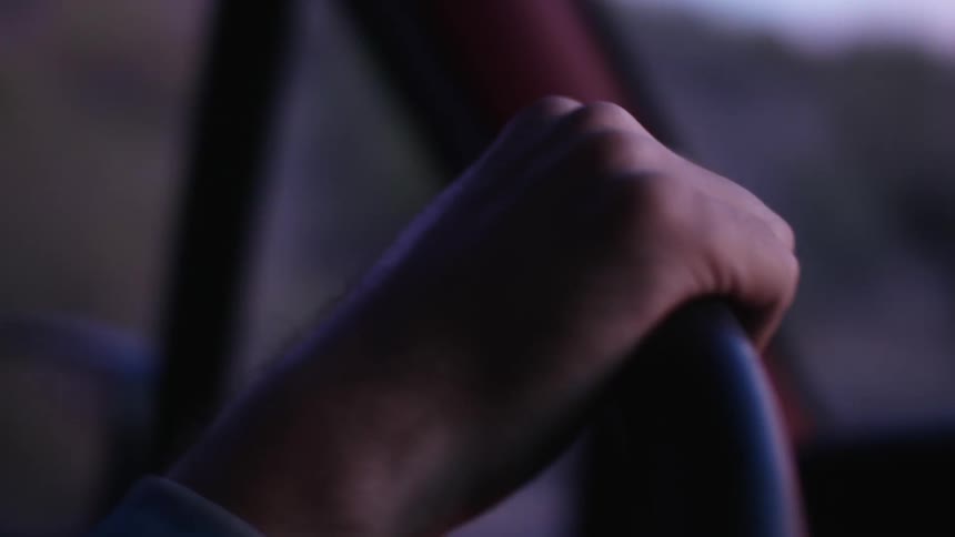 Close up of a mans hand on a steering wheel as he drives