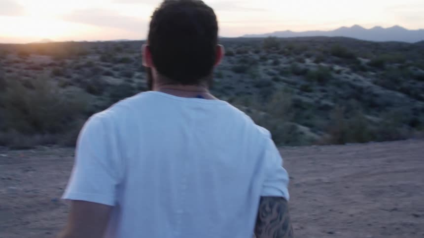 A man in an open field takes off his jacket