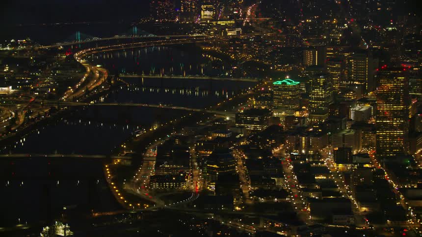 Zoom out reveal of the many bridges spanning the Willamette River in downtown Portland Oregon under a dark night sky showing skyscrapers and the downtown grid