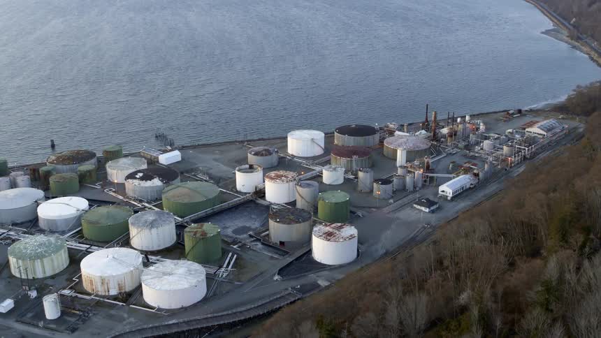 Pullback tilt up reveal of an industrial tank farm complex on the coast