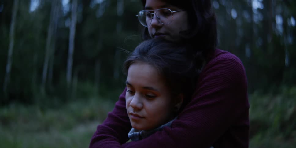 Two women watch the campfire