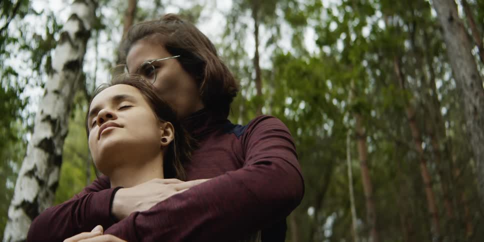 Two teenager girls hug and one girl kisses the other on the head