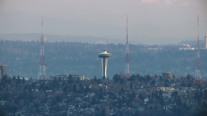 The space needle in Seattle sits high on a ridge with radio antennae and SeaTac airport visible in the background