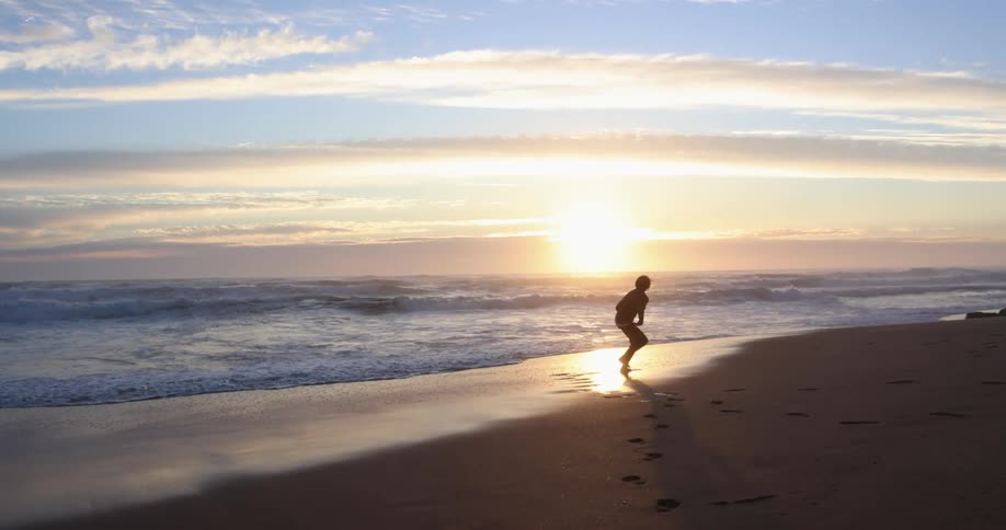 A person running on the beach as the sun sets