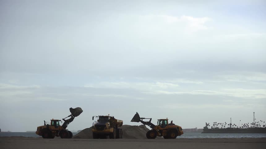 Bulldozers on a beach moving sand