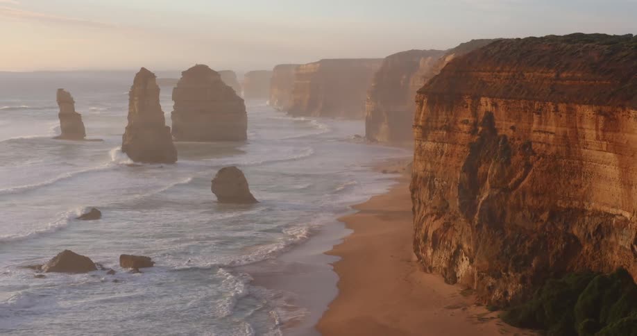 Waves crash onto a beach lined with cliffs