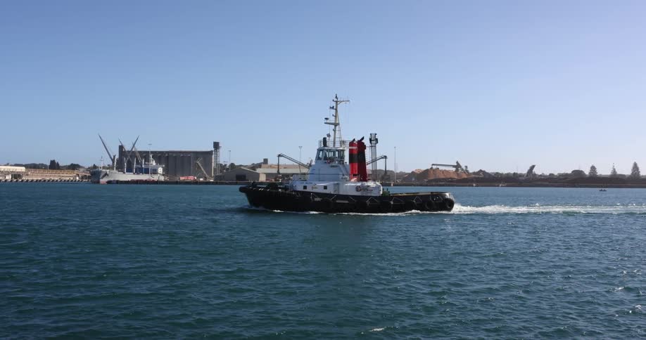 Commercial boat leaves wake moving through the water in parallel to the shore