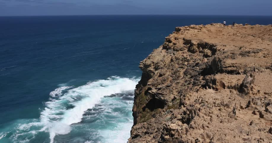People stand on promontory looking out to sea