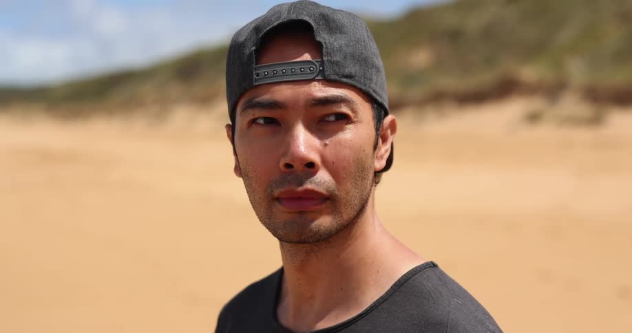 A man stands alone on an empty beach near the ocean
