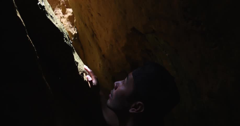 A man standing between two cliffs looks around
