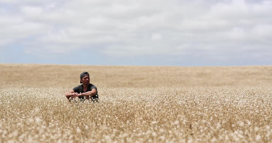 A man is sitting in the tall yellow grass