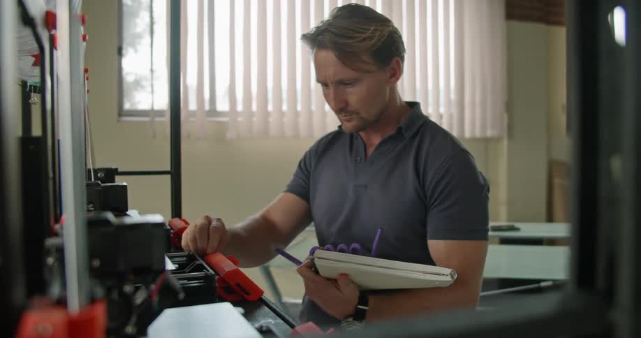 A man that is working with some 3d printers