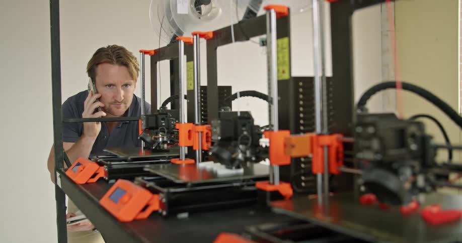 A man that is watching multiple 3d printers