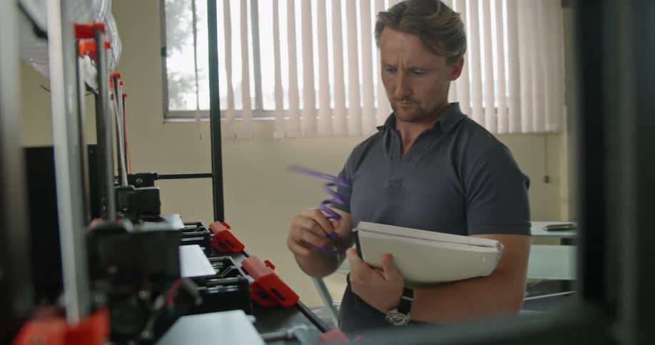A man that is checking things on a 3d printer