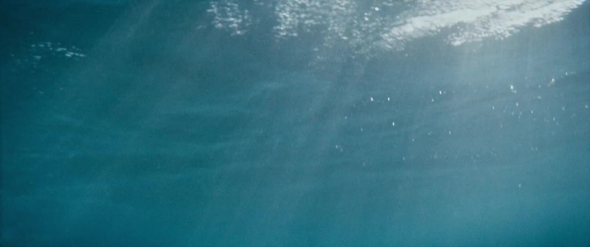 Underwater in the ocean with waves with the sky and clouds above