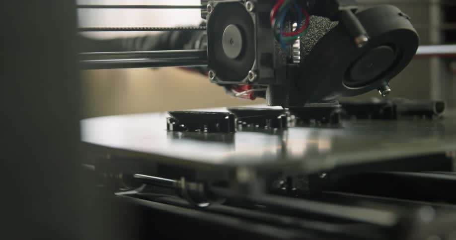A 3d printer printing with a wall in the background