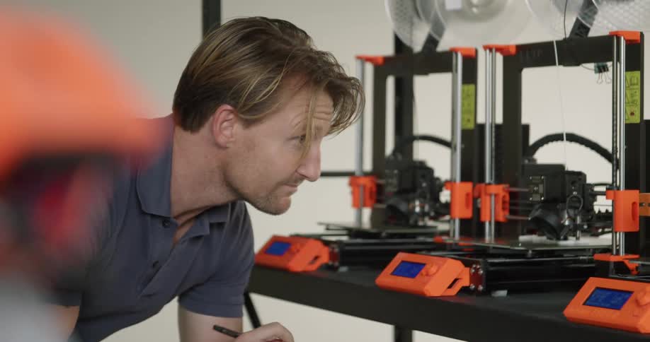 A man takes notes as he watches a 3d printer