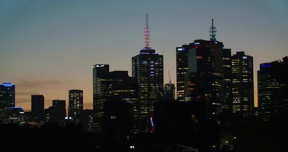 A bird flies past the city at sunset