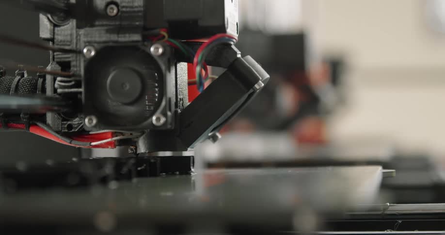 A 3d printer printing with a wall in the background
