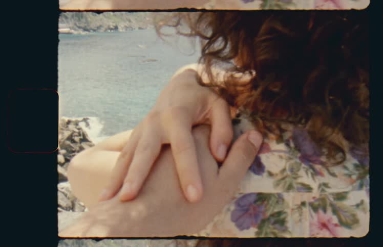Man reaches out to womans shoulder sitting on beach
