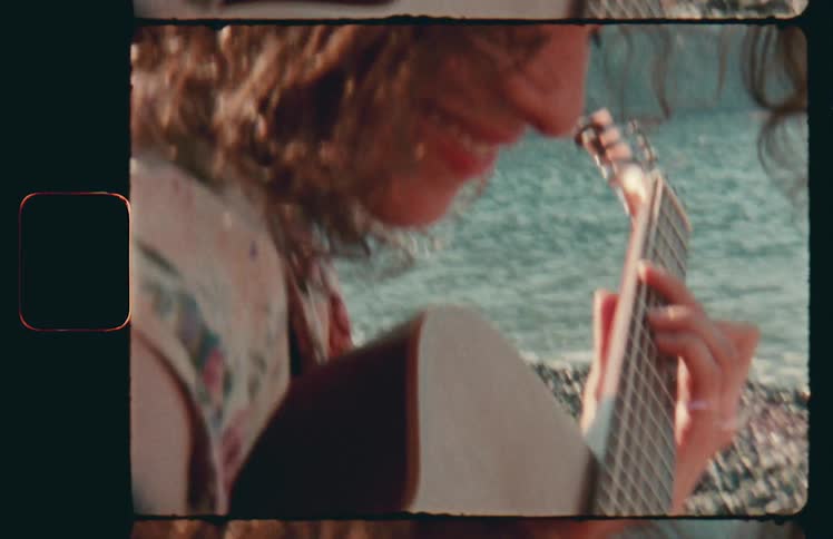 Woman playing guitar near the coast of a lake