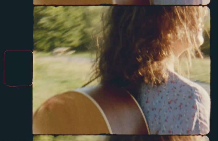 A woman with a guitar on her back walks along a path