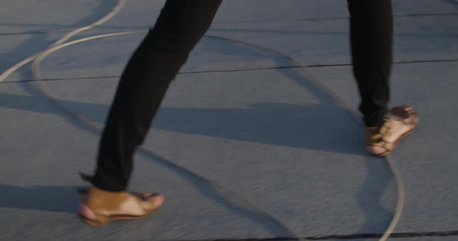 A person in sandals walks on concrete