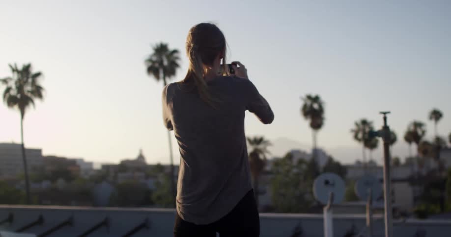 A woman takes a picture with a smart phone at dusk
