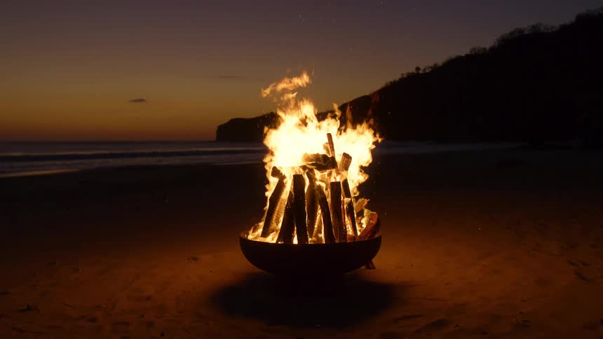 Bright flames from a bonfire on a beach after the sun has set