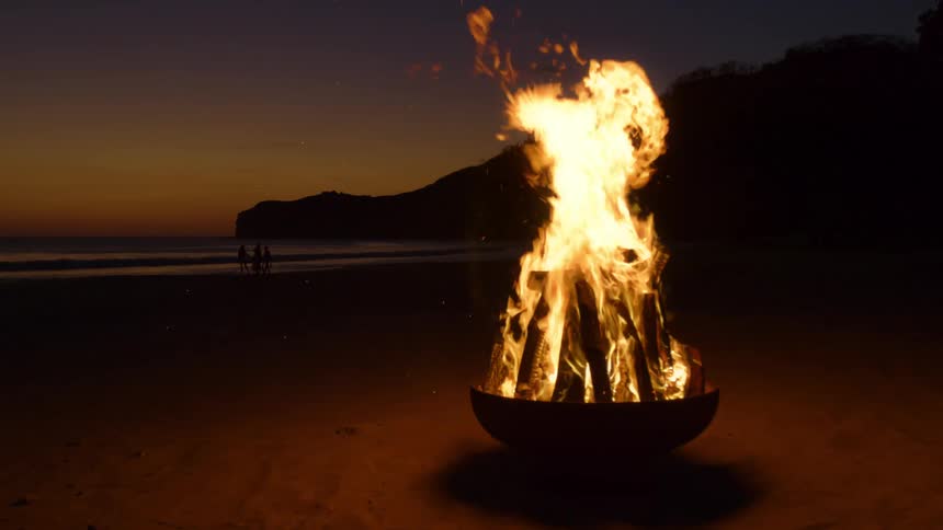 A view of a fire burning in a pit out at the beach