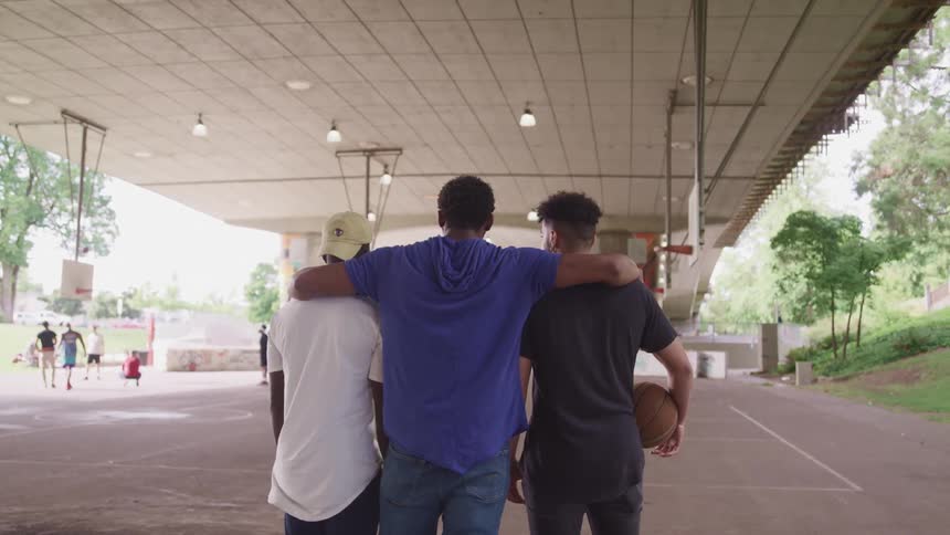 Friends stand on covered basketball court watching others play