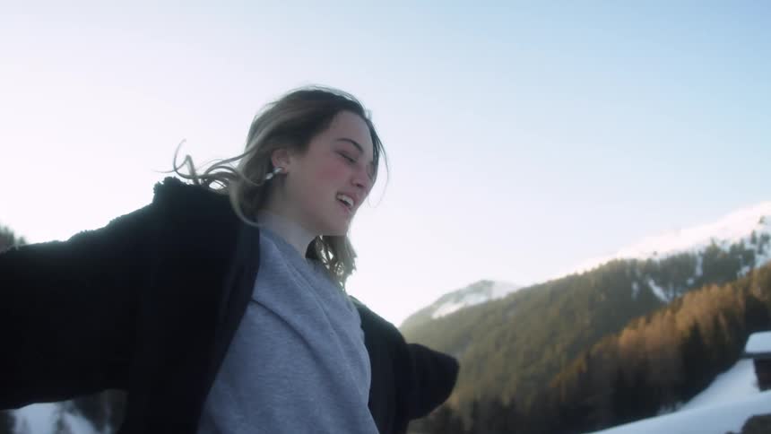 A woman is dancing outside by the mountains