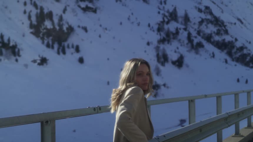 A woman walks along a guardrail on a rural mountain highway
