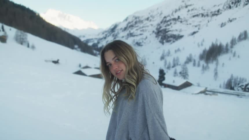 A teenage girl at the base of a mountain takes her jacket off