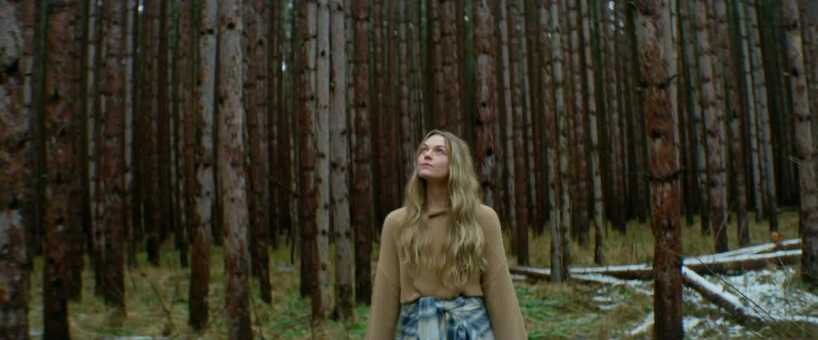 Woman standing in the forest looking up