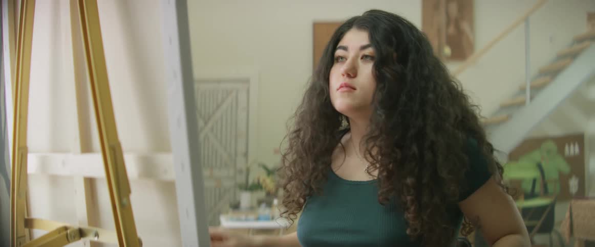Painter checks her phone before continuing painting on canvas