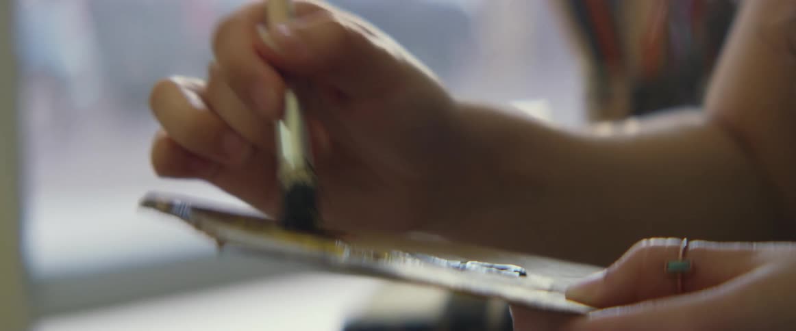 A woman painting rubs her brush in paint