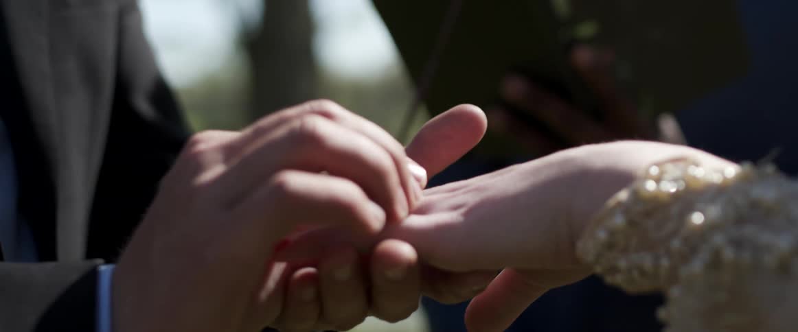 A man putting a ring on a womans finger at a wedding