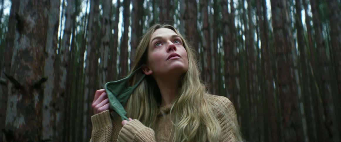 A woman removing a face mask while hiking alone in a forest