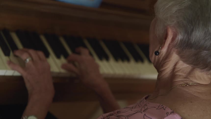 An elderly woman playing the piano