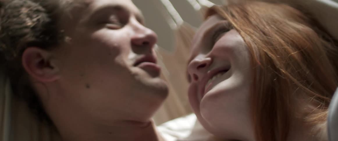 A man kissing a womans forehead while smiling and cuddling