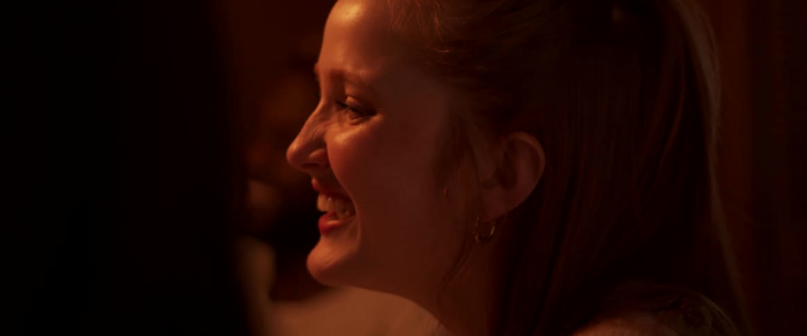 Sitting friends smile and laugh in dimly lit room
