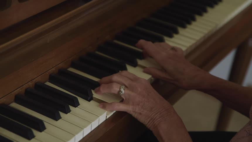 A woman sits and plays the piano