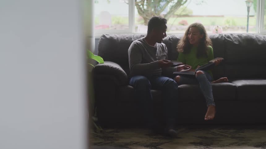 Father and daughter looking at a photo album in the living room at home