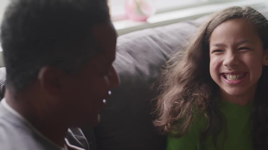 A man and a girl in a room sitting on a couch and smiling