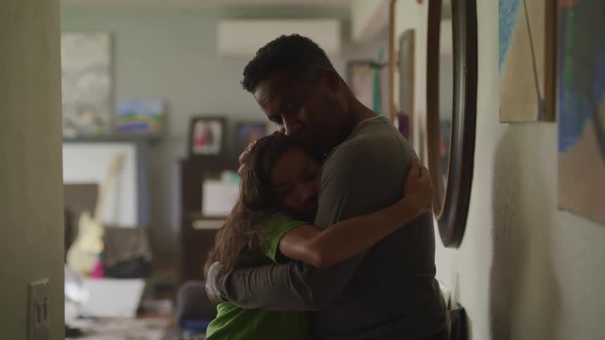 Father hugs daughter stroking her hair while standing in living room