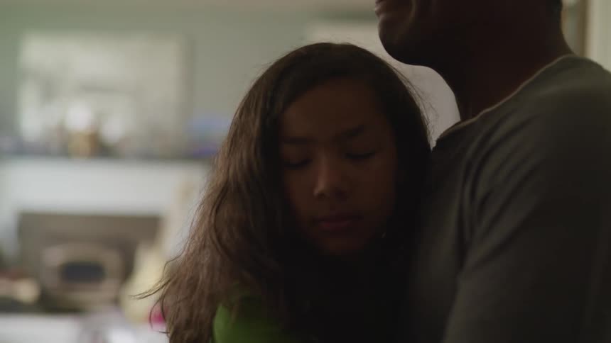 Father hugs daughter in the living room at home