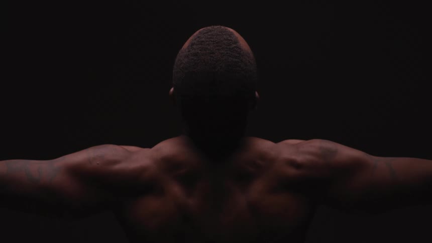 A man stretching in a room with a black background