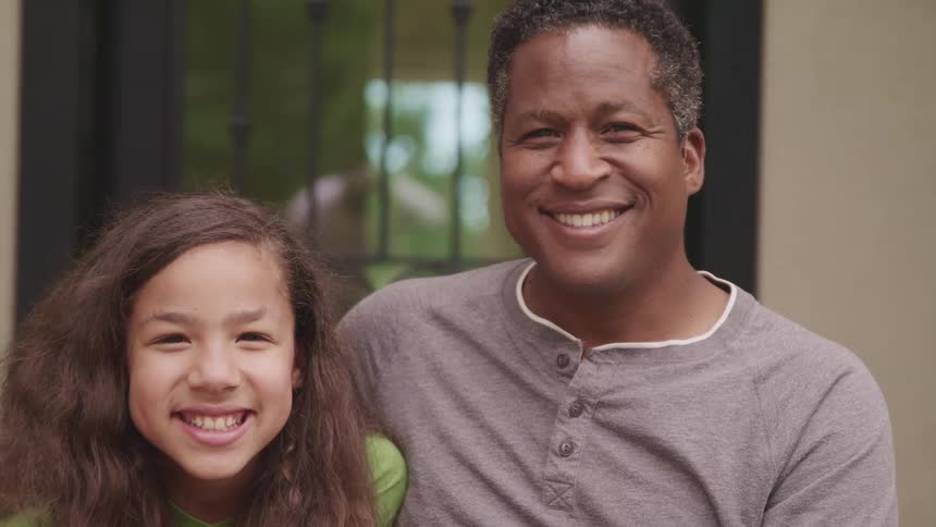 A portrait of a father and daughter smiling