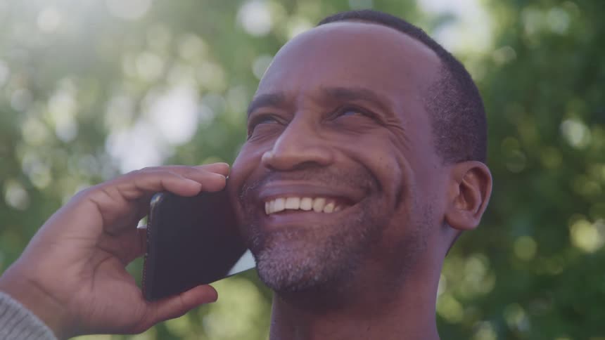 A smiling man talking on his cell phone outdoors